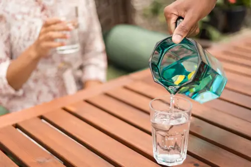 Person pours jug of water into a glass